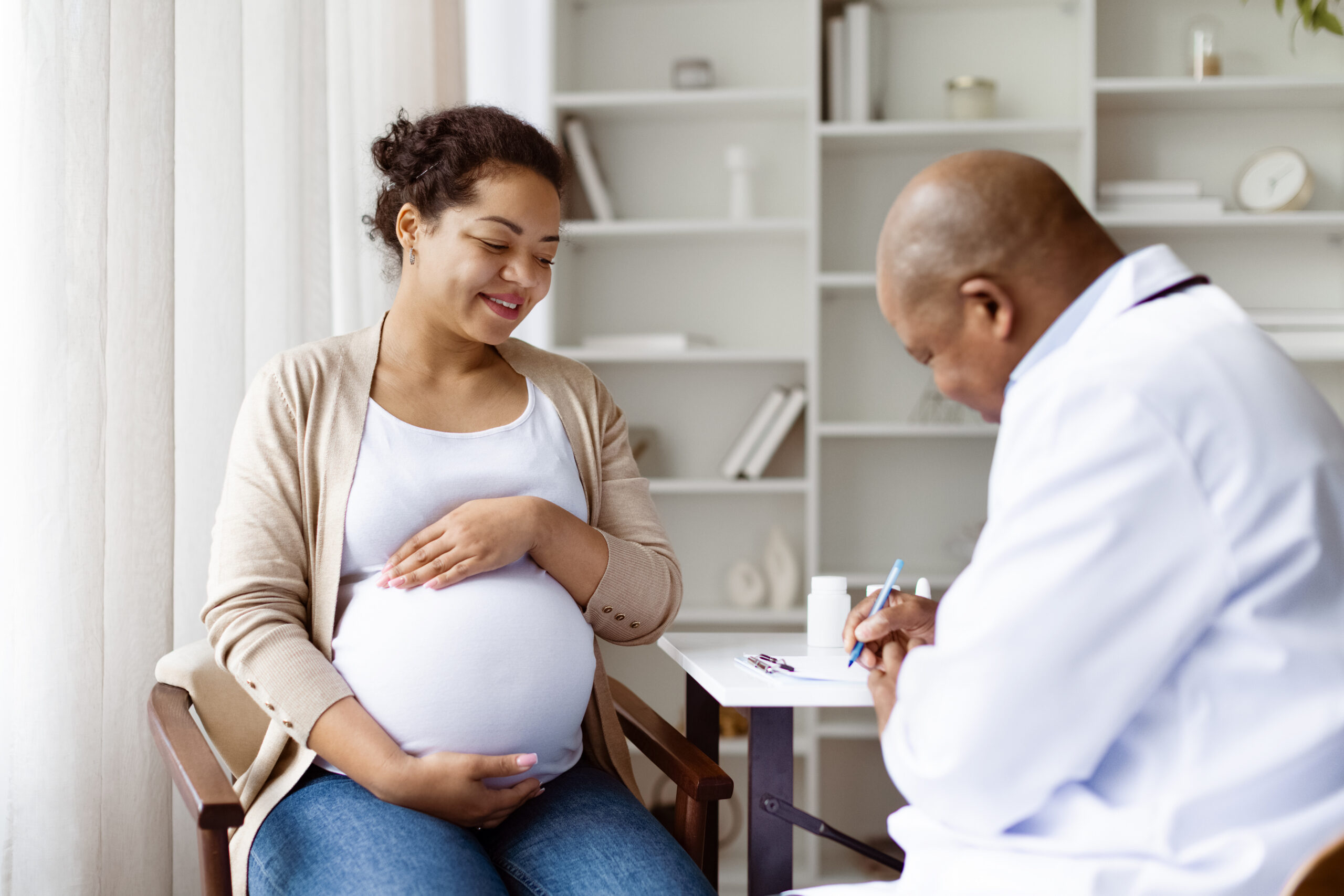 Pregnancy Check Up. Professional black obstetrician listening to patient and writing record